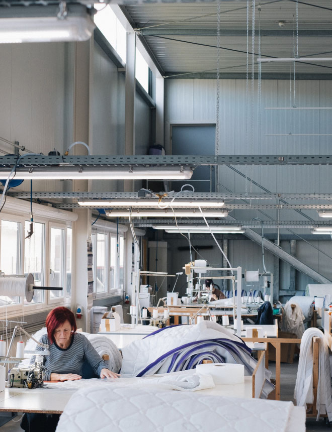 PH-factory-hall-woman-sew@2x Intelligente Gebäudeautomation von Loxone in einem Betrieb.